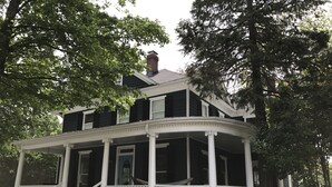 A two-story house with a covered porch and a brick chimney. - Serene Sauna Retreat with Chefs Kitchen, Luxury Beds & Luxury Baths (West Point)