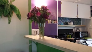 Une cuisine avec un plan de travail vert, un vase rempli de fleurs, une cuisinière et un four à micro-ondes.