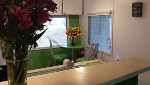 Une cuisine avec un plan de travail vert, un vase rempli de fleurs roses et une fenêtre donnant sur l’extérieur.