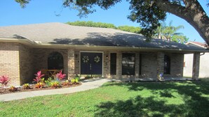 A two-story house with a brick facade, a front porch, and a well-maintained lawn.