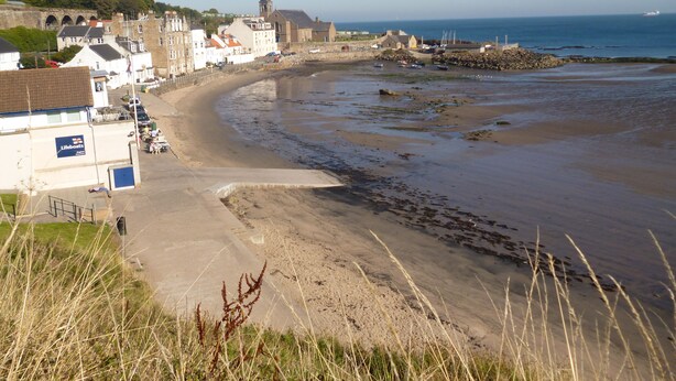 Une ville côtière dotée d’une plage de sable, d’une station de sauvetage en mer et de bâtiments historiques.