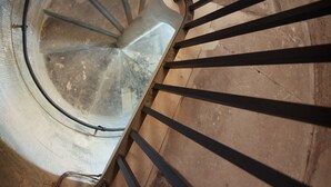 Un escalier en colimaçon avec des rampes en métal et un mur en béton.