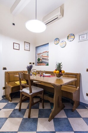 A dining area with a wooden table, benches, and a bowl of fruit. - Beautiful apartment sleeps  in the city centre of Florence (Firenze)