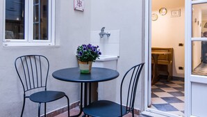 A small patio with a round table and two chairs, a potted plant, and a window. - Beautiful apartment sleeps  in the city centre of Florence (Firenze)
