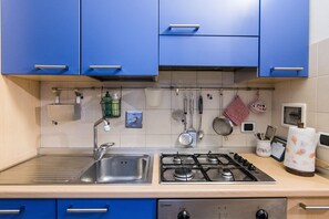 A kitchen with blue cabinets, a stainless steel sink, a gas stove, and various kitchen utensils and appliances. - Beautiful apartment sleeps  in the city centre of Florence (Firenze)