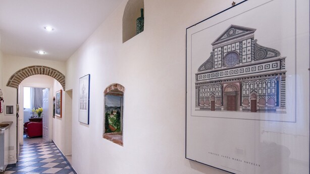A hallway with a checkered floor, framed artwork on the walls, and a large architectural drawing. - Beautiful apartment sleeps  in the city centre of Florence (Firenze)