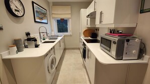 A compact kitchen with a washing machine, a microwave, and a sink. - A Little Gem in The West Highlands, Argyll Inveraray Loch Fyne views, sleeps 4 (Inveraray)
