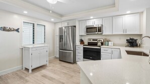 Cocina moderna con armarios blancos, electrodomésticos de acero inoxidable y una isla central.