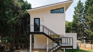 A modern two-story building with a balcony, a staircase, and a door.