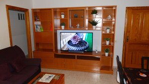 A living room with a wooden entertainment unit, television, and various decorative items.