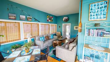 A living room with a teal wall, a sofa, a coffee table, and a bookshelf.