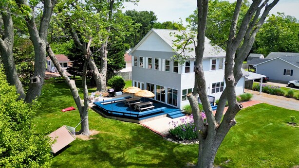 A two-story house with a backyard swimming pool, surrounded by trees and a well-maintained lawn.