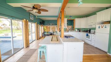 A spacious kitchen with a large island, white cabinets, and a dining area with a table and chairs.