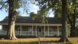 A two-story house with a porch, a front door, and a mailbox. - Quiet, Private, 2 acres to enjoy and still close to everywhere you want to go. (Elkins)