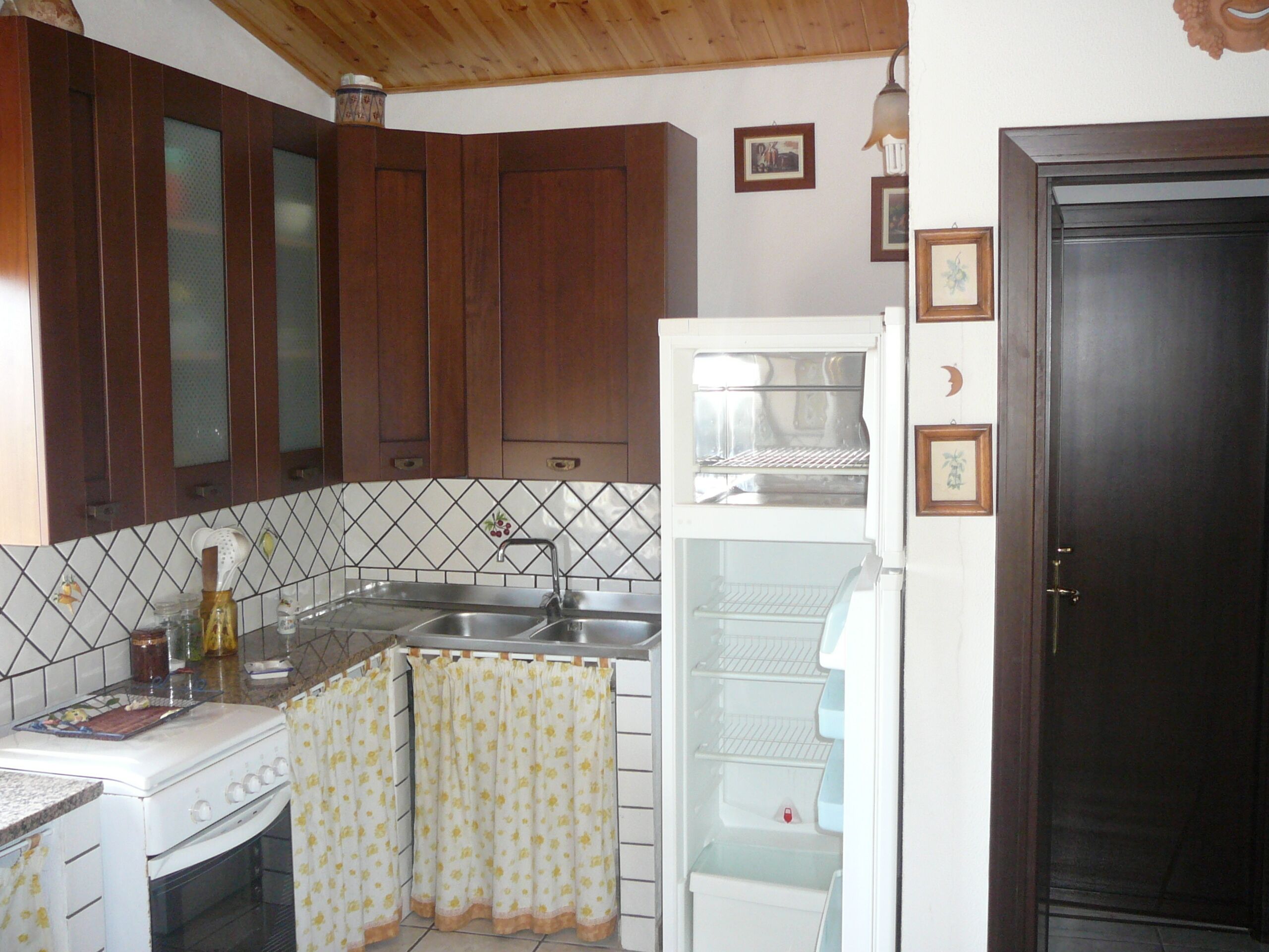 Una cocina con armarios de madera, un refrigerador blanco, una estufa y un lavamanos.