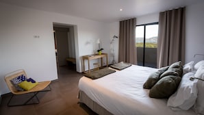 A modern hotel room with a large bed, a desk, and a view of the outdoors. - New: Villa 200 m2 with sea view and heated swimming pool, 4 bedrooms. (Porto-Vecchio)