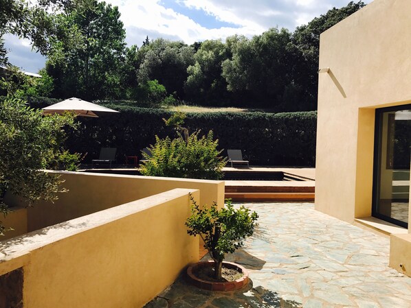 A courtyard with a stone floor, a small tree, and a bench. - New: Villa 200 m2 with sea view and heated swimming pool, 4 bedrooms. (Porto-Vecchio)