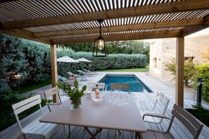 An outdoor patio with a pool, wooden deck, and seating area. - New: Villa 200 m2 with sea view and heated swimming pool, 4 bedrooms. (Porto-Vecchio)
