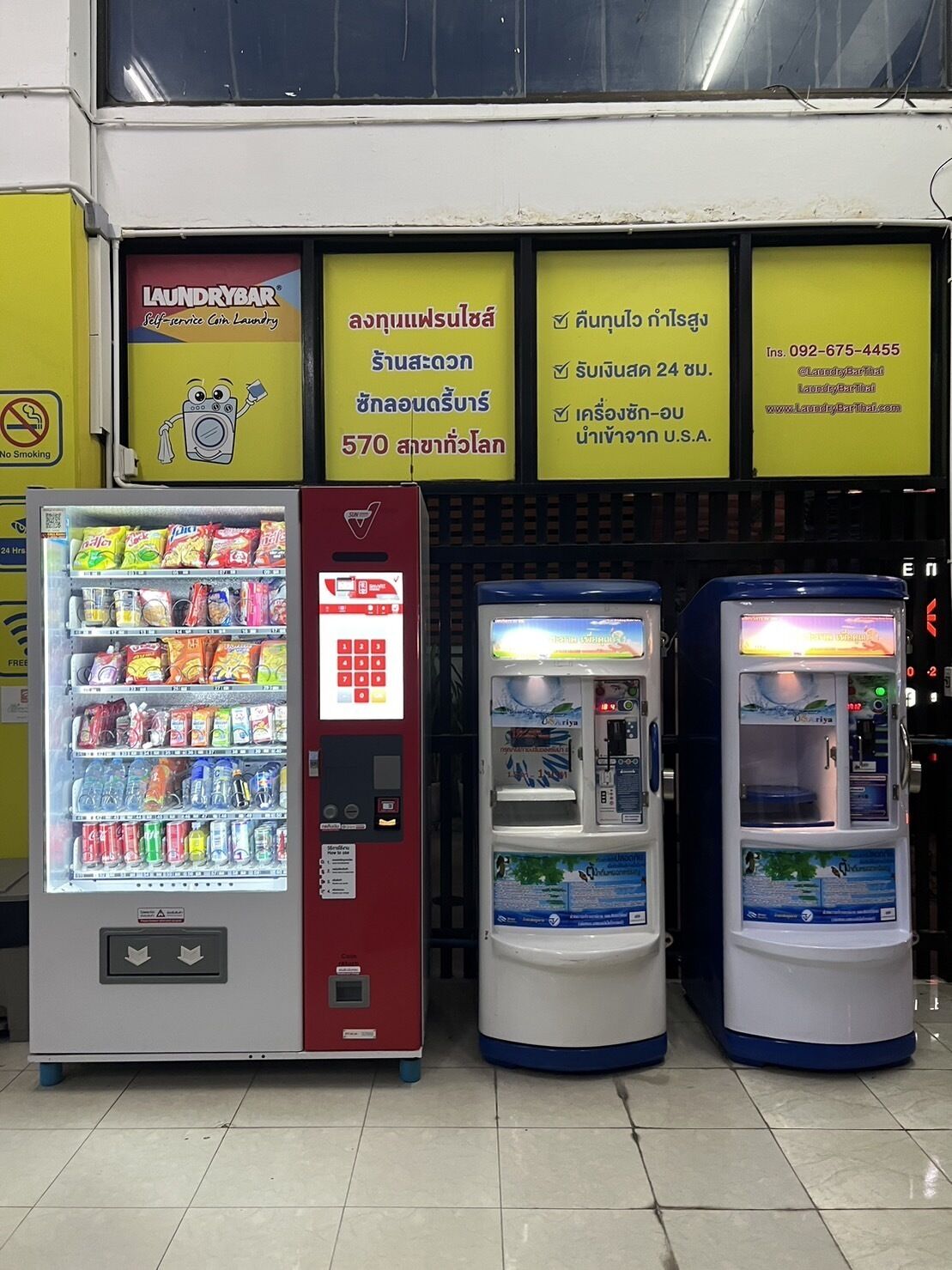 A laundromat with self-service machines, vending machines, and a no-smoking sign.
