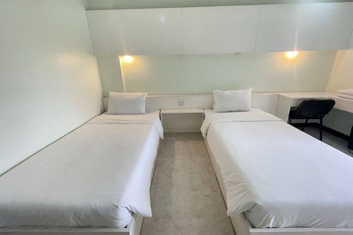 Una habitación con dos camas individuales, un escritorio y una silla.