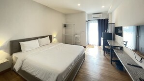 A modern hotel room with a large bed, a desk with a chair, a wardrobe, and a shower area. - Chonlapruk Lakeside Hotel (Khon Kaen)