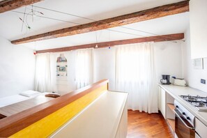 A compact kitchen with wooden beams, a white countertop, and a stove.
