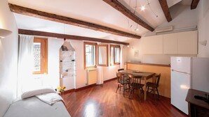 A compact room with a bed, a dining table with chairs, a small kitchen area with a refrigerator, and wooden beams on the ceiling. - Ca' Marina, a few steps from the Biennale di Venezia (Venezia)