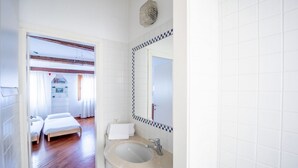 A hotel room with a wooden floor, a bed, a bathroom with a sink and mirror, and a view of another room with a bed and a window. - Ca' Marina, a few steps from the Biennale di Venezia (Venezia)