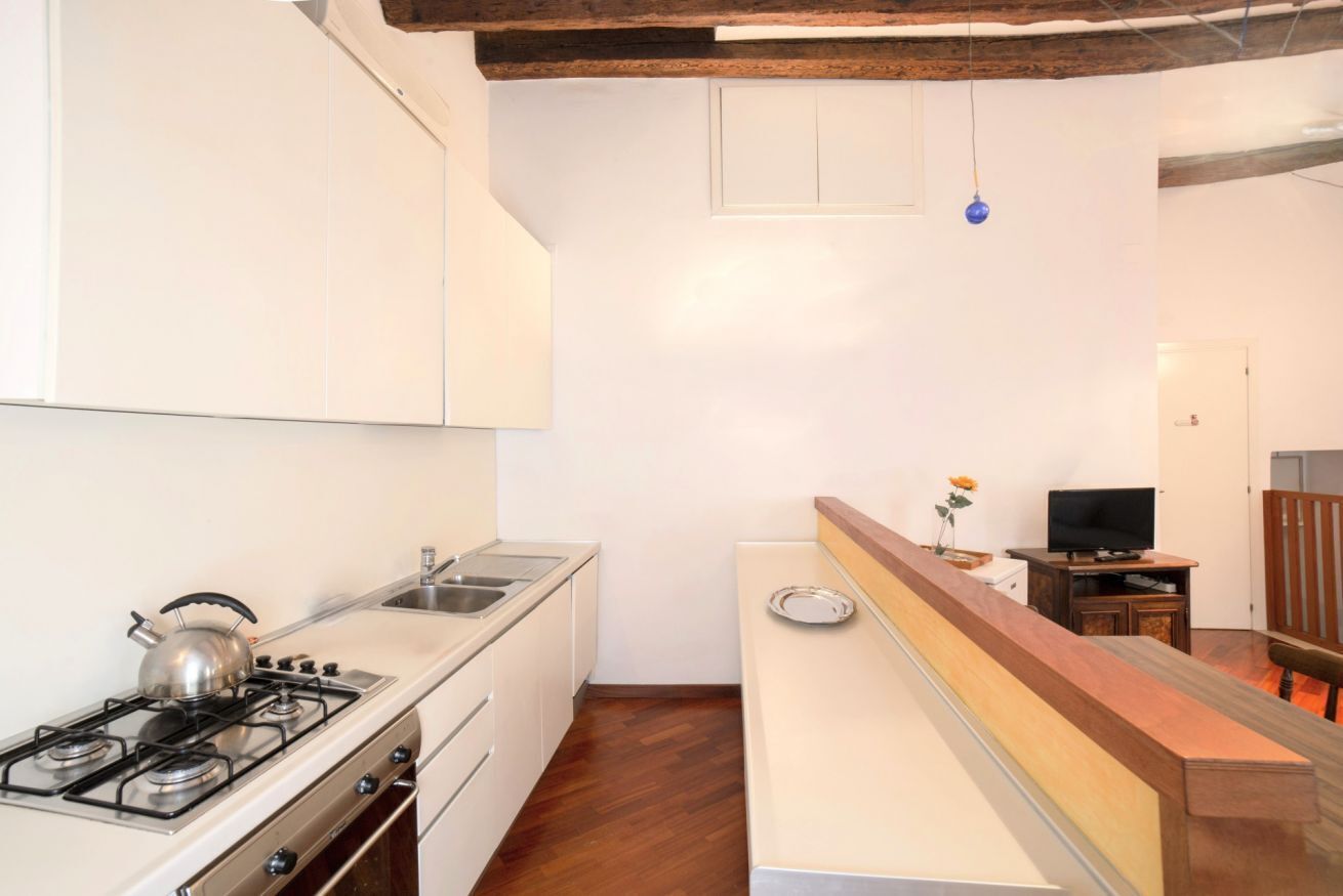Una cocina compacta con estufa a gas, pileta y alacenas de madera.