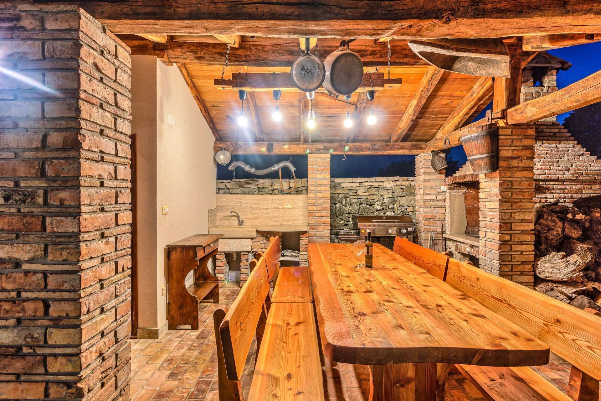 Ein rustikales Holzinnere mit einem langen Esstisch, Steinwänden und einem Kamin aus Stein.