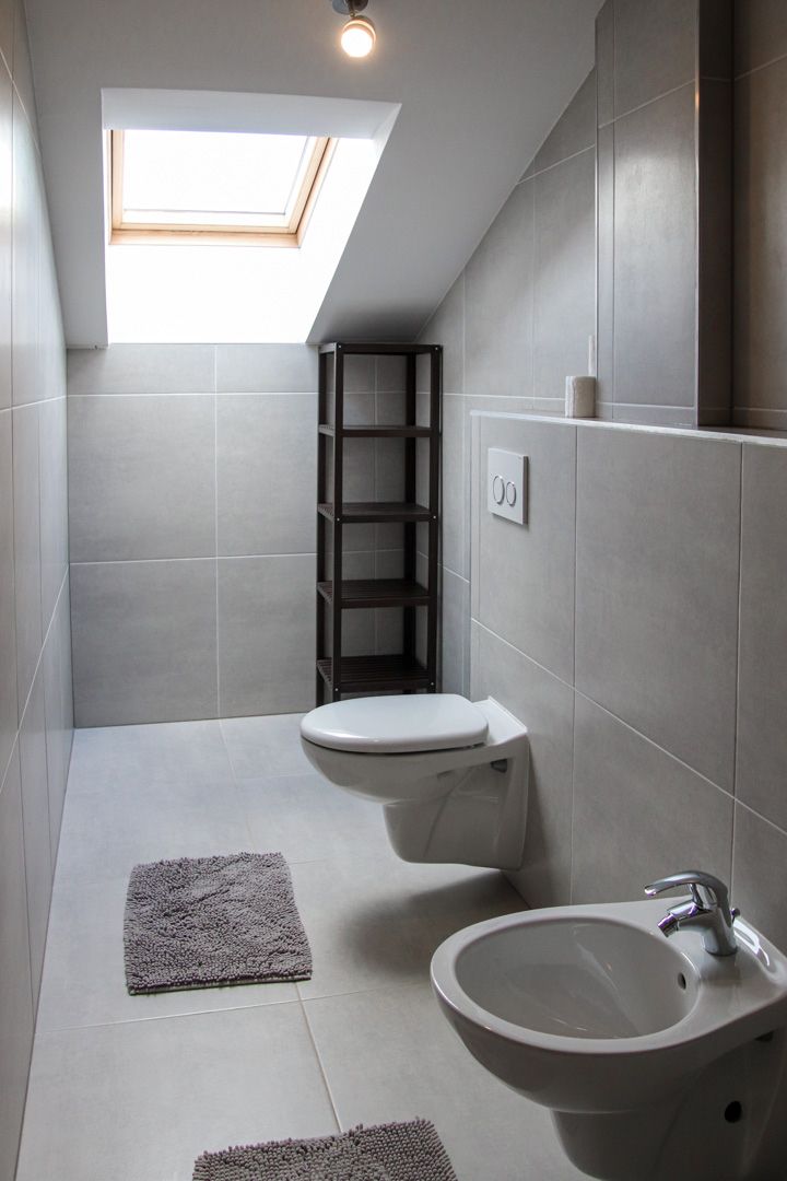 Un baño moderno con tragaluz, inodoro, bidé y lavamanos.
