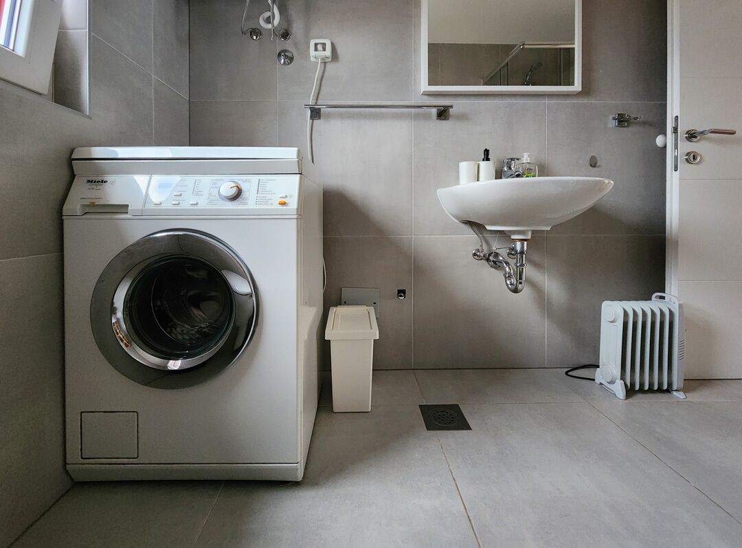 Ein modernes Badezimmer mit einer Waschmaschine, einem Waschbecken und einem Heizkörper.