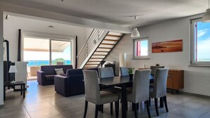 Una sala de estar moderna con comedor, una escalera y un gran ventanal con vistas.