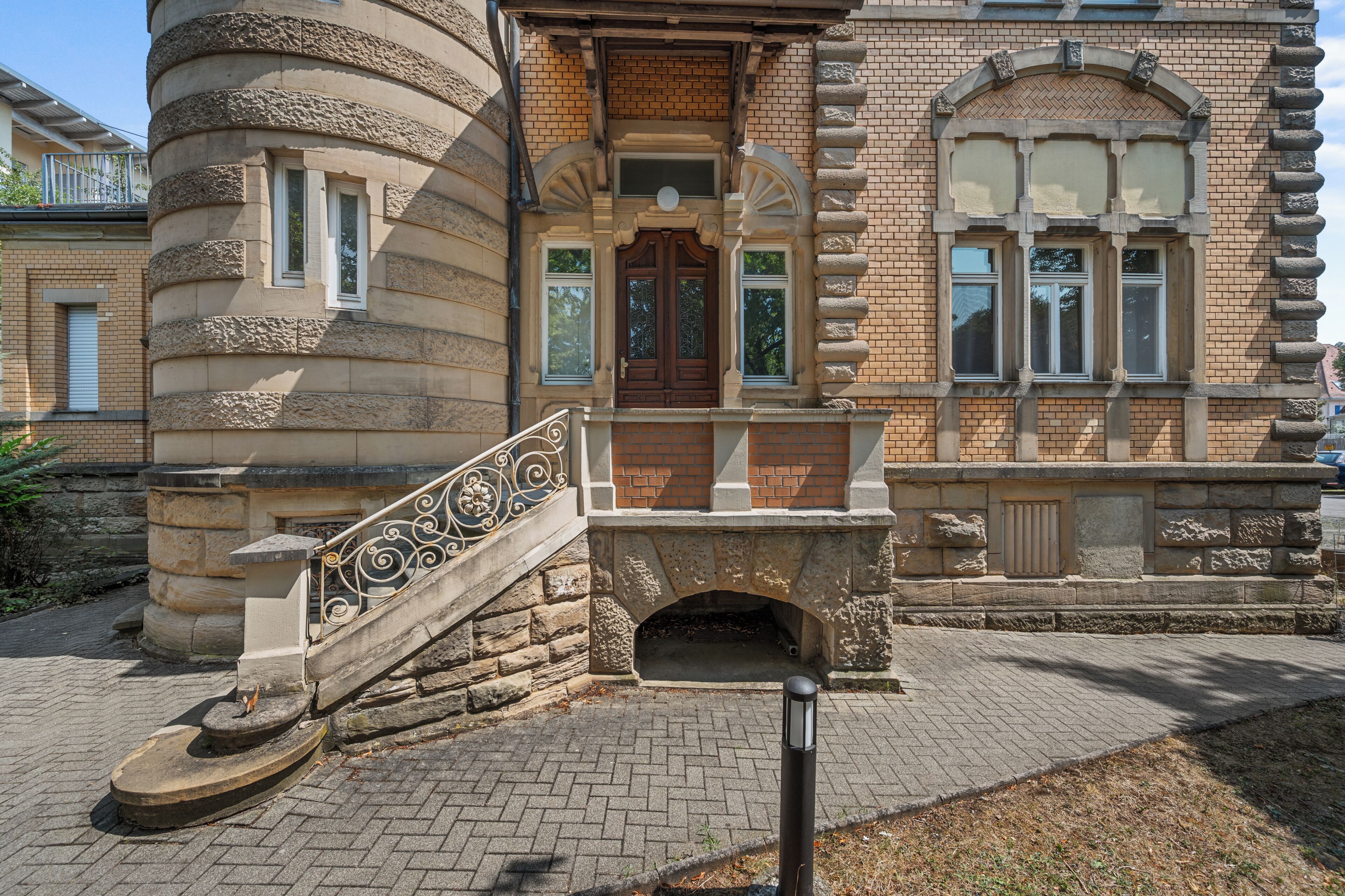 Ein historisches Gebäude mit einer Steintreppe, die zu einer Holztür führt, Ziegelwänden und einem Steinbalustraden.