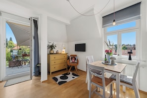 Un interior moderno con zona de comedor, sofá, televisor y ventana con vistas.