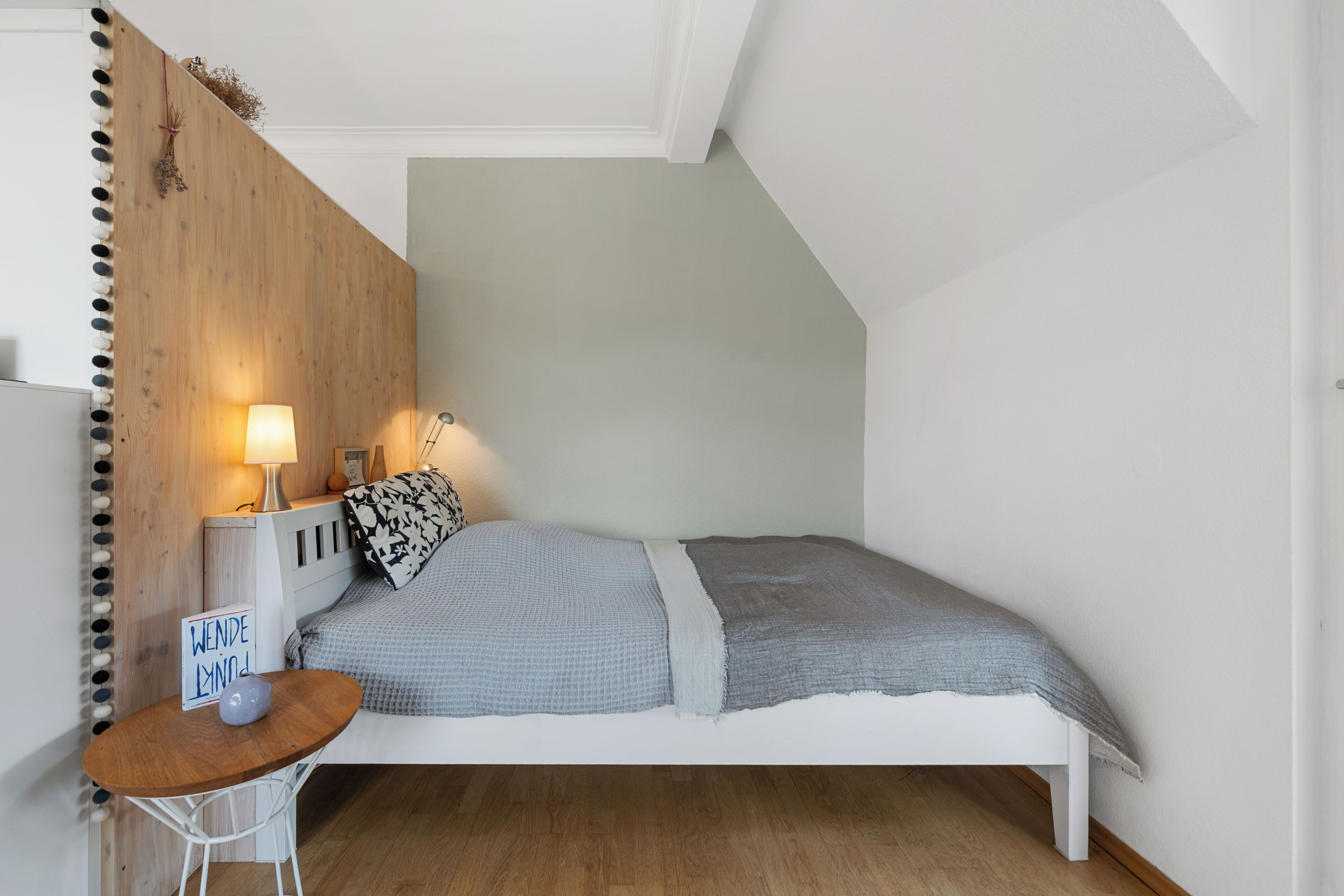 Ein Schlafzimmer mit Bett, Nachttisch, Lampe und einem Schild.