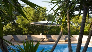 Zona de piscina amb gandules i una ombra.