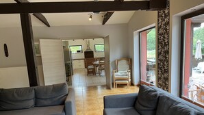 A modern living room with two grey sofas, a wooden dining table, and a patterned chair. - Standalone idyllic holiday home in the middle of nature for 6 to 8 people (Grabow)