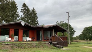 A rustic cabin with a porch, outdoor seating, and a satellite dish. - Standalone idyllic holiday home in the middle of nature for 6 to 8 people (Grabow)