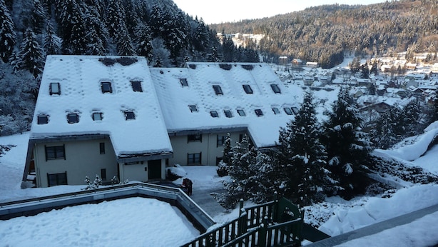 Un bâtiment recouvert de neige, doté de nombreuses fenêtres et d’un escalier menant à son entrée.