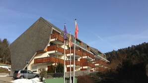 Un immeuble à plusieurs étages doté de balcons, d’un mât pour drapeau et dont le sol est recouvert de neige.