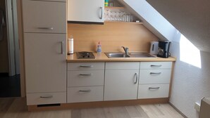 Une cuisine compacte équipée d’un réfrigérateur encastré, d’un évier et d’une machine à café.