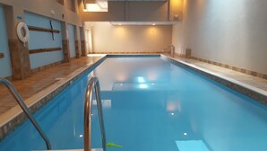 Une piscine intérieure offrant une vue dégagée sur le bord du bassin, avec un poste de surveillance pour les sauveteurs et un mur recouvert de carreaux.