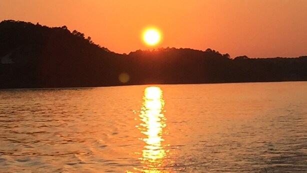 A sunset over a body of water with a silhouette of a hill in the background. - Quiet, Charming Lake Front Home with Kayaks, 2 Guest Maximum (Hot Springs)