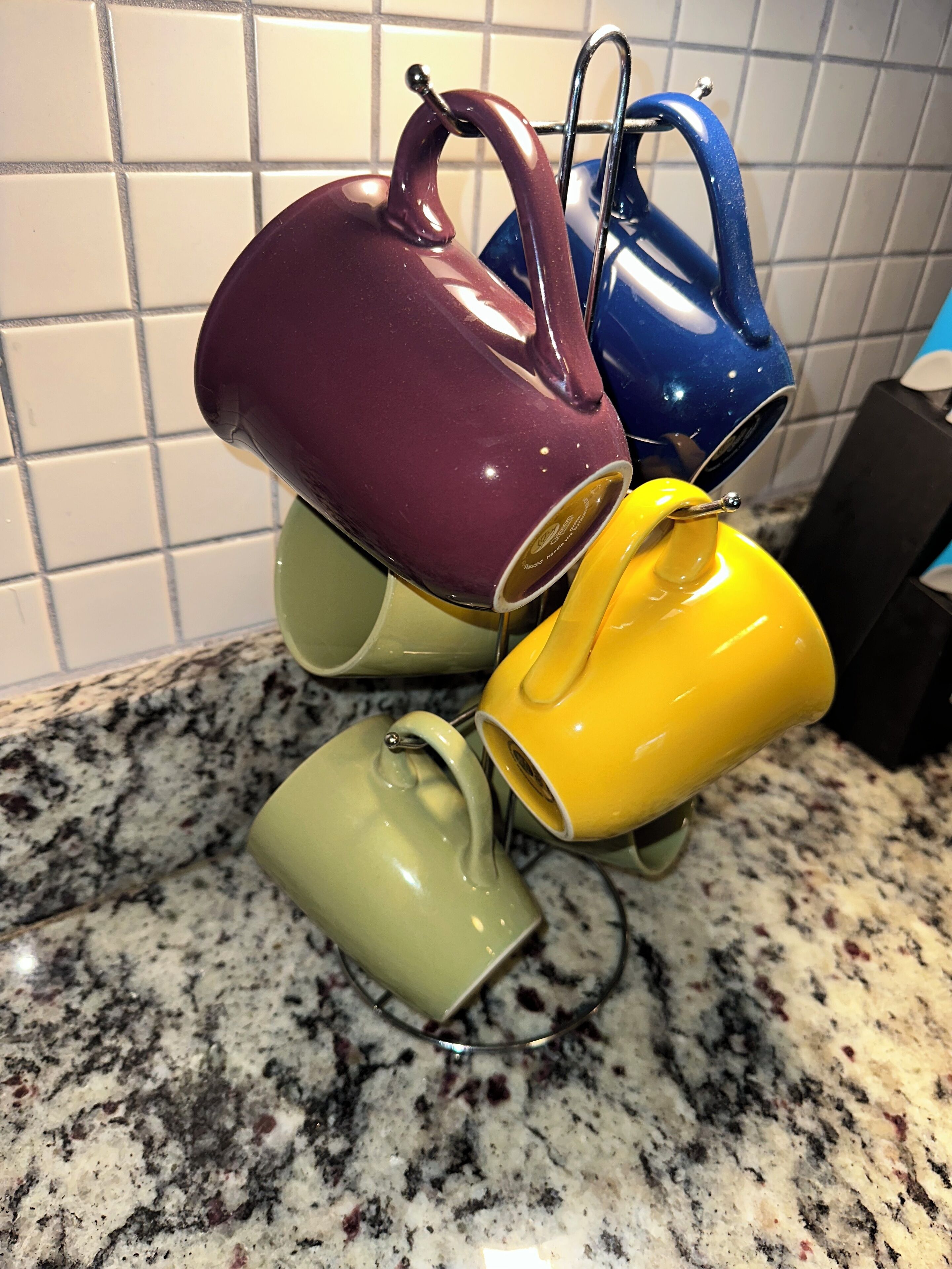 A kitchen counter with four mugs in different colors.