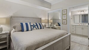 A bedroom with a large bed, a nightstand, a dresser, a mirror, and a ceiling fan. - Oceanfront Romantic Getaway-Including Free Beach Chair Service! (Panama City Beach)