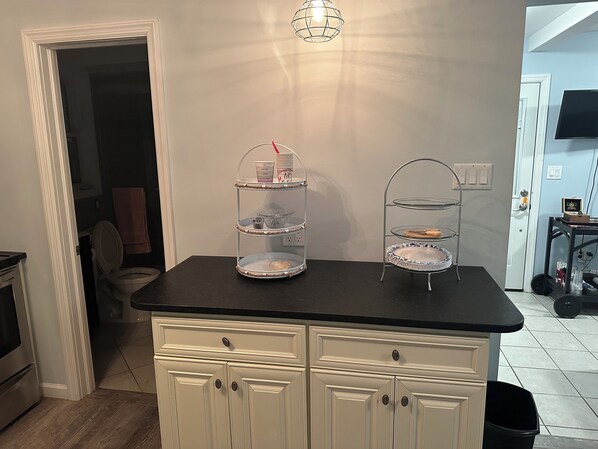 A kitchen with a black countertop, white cabinets, and a three-tiered serving tray.