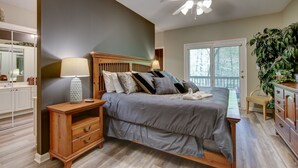 A bedroom with a bed, bedside table, lamp, and a ceiling fan.