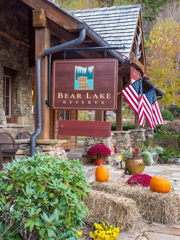 A wooden sign for Bear Lake Reserve with a rustic stone building in the background.