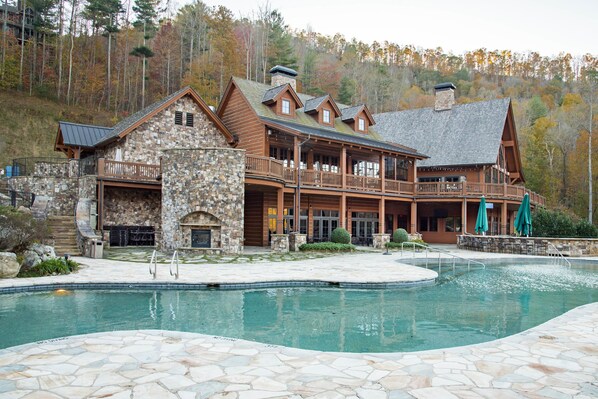 A lodge with a stone exterior, a swimming pool, and a large deck area.